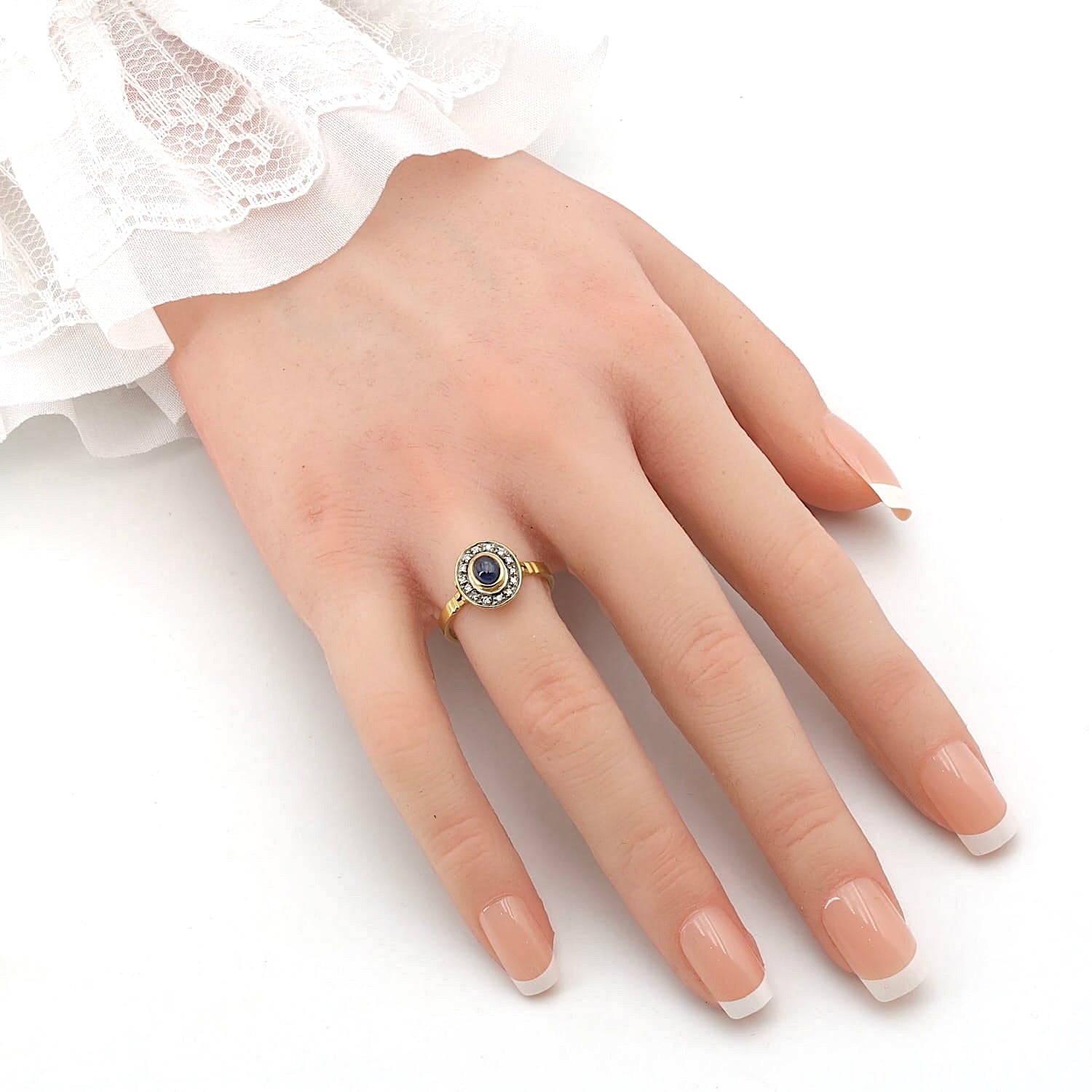Ring in 750 yellow gold with a blue sapphire cabochon and diamonds, on the hand