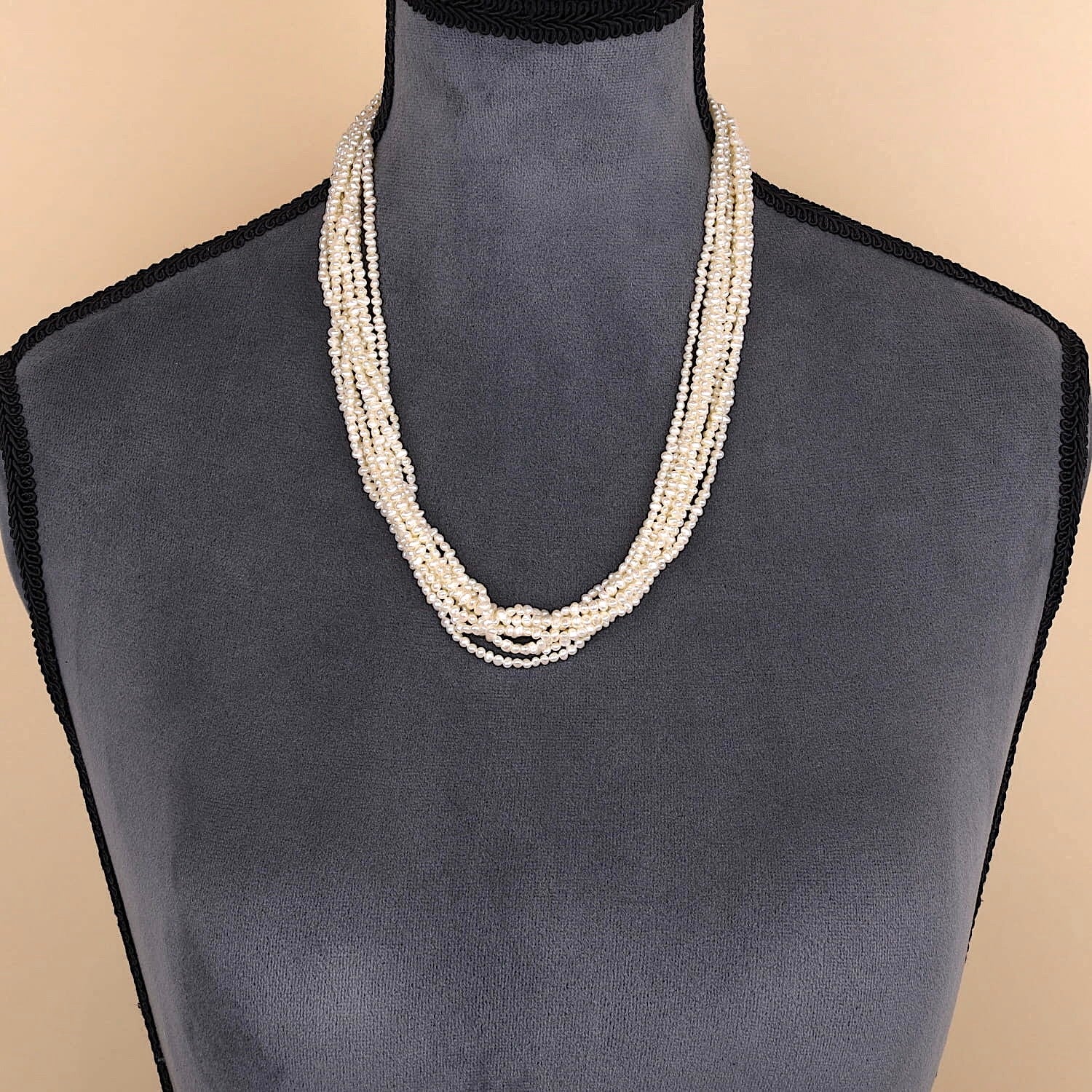 Necklace with 8 intertwined rows of cultured pearls and a silver lock, on the bust