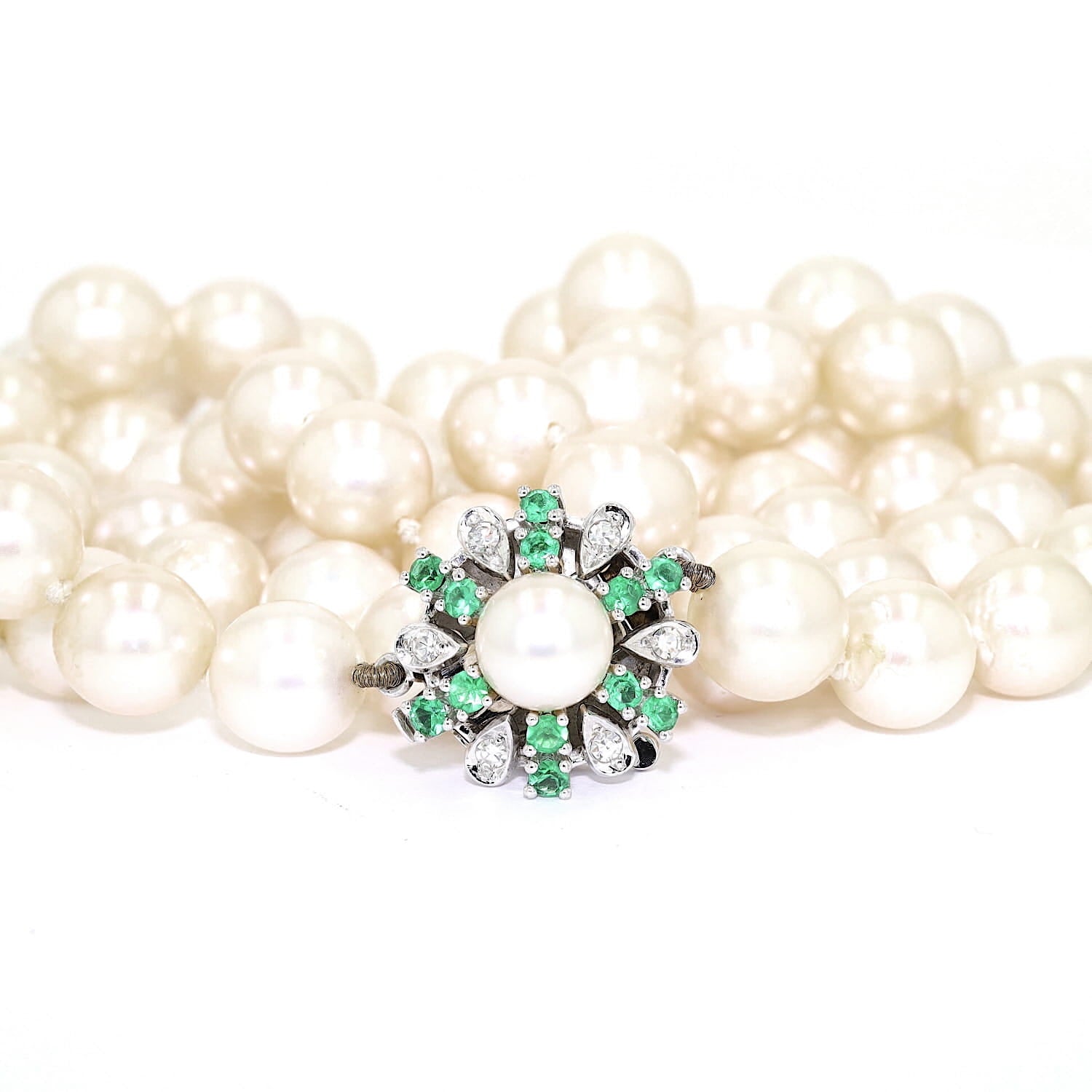 Akoya cultured pearl necklace with a 585 white gold clasp with diamonds and emeralds, lying frontally