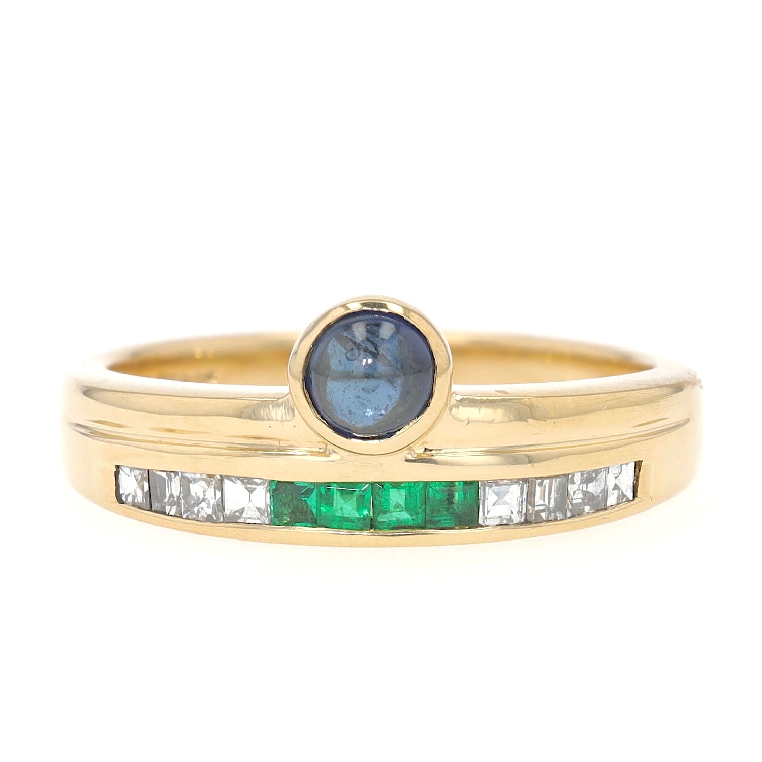 Buchwald ring in 750 yellow gold with diamonds, emeralds and a sapphire cabochon, lying frontally