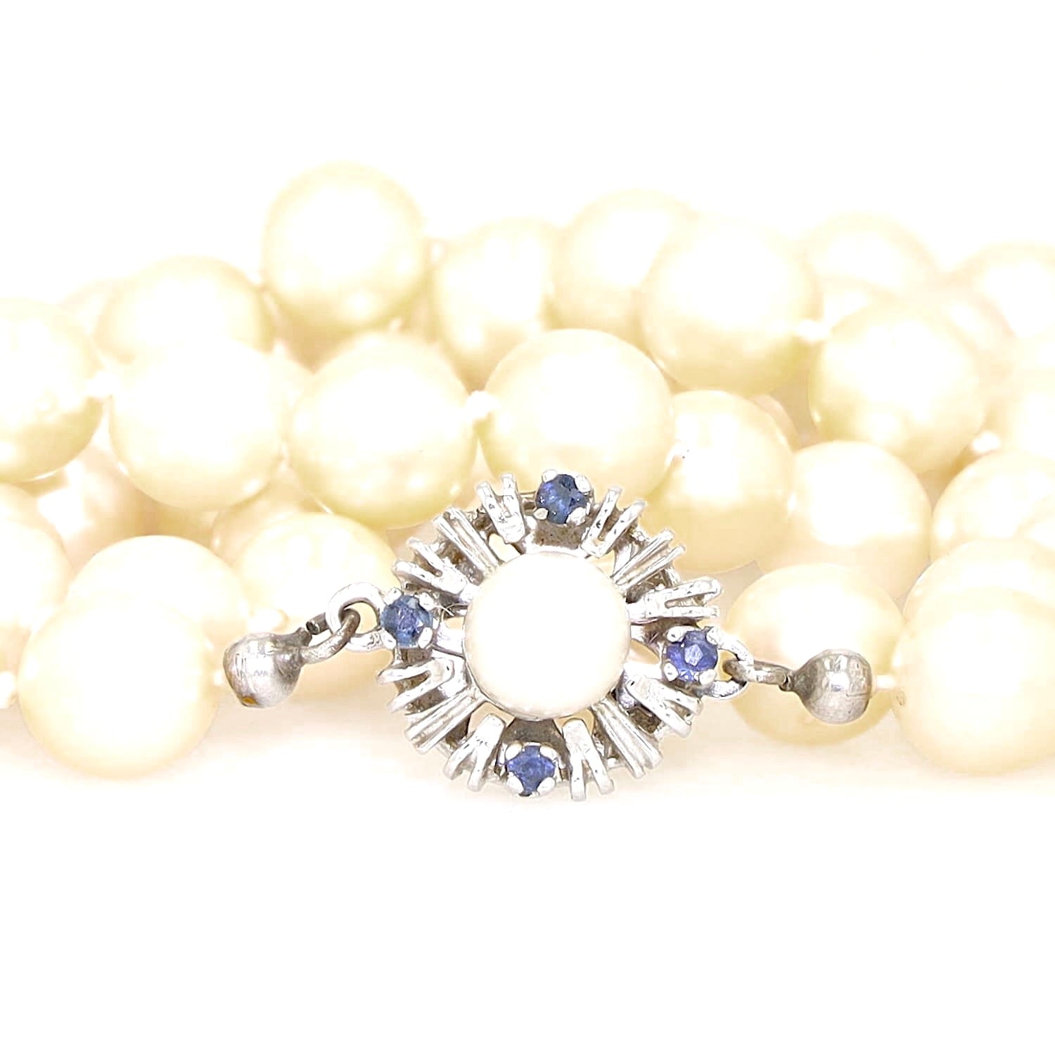 Akoya cultured pearl necklace with a 585 white gold clasp with sapphires, lying close, coiled, clasp from the front