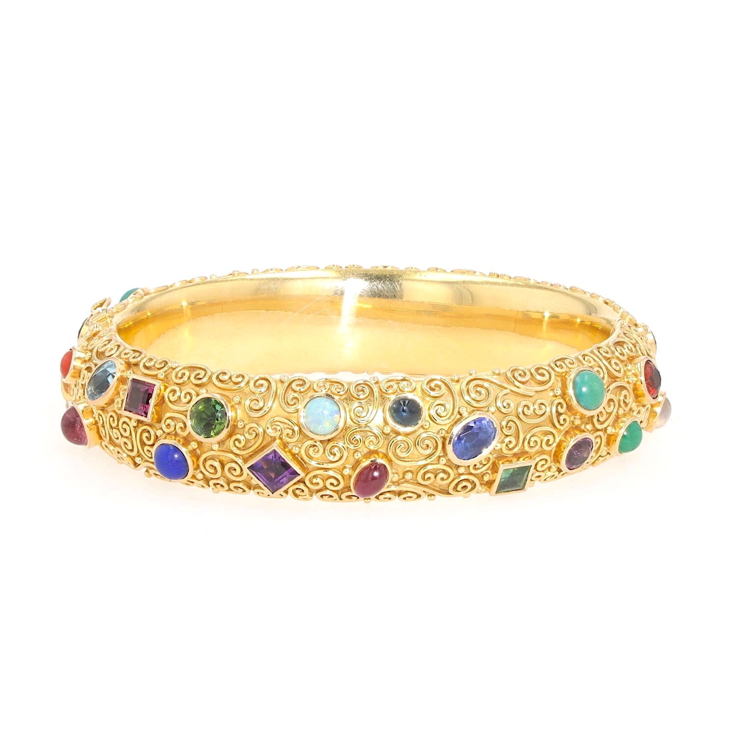 Bangle by Eugen Hirner in 750 yellow gold with various colorful gemstones, lying frontally