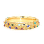 Bangle by Eugen Hirner in 750 yellow gold with various colorful gemstones, lying frontally