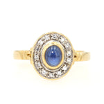 Ring in 750 yellow gold with a blue sapphire cabochon and diamonds, lying frontally
